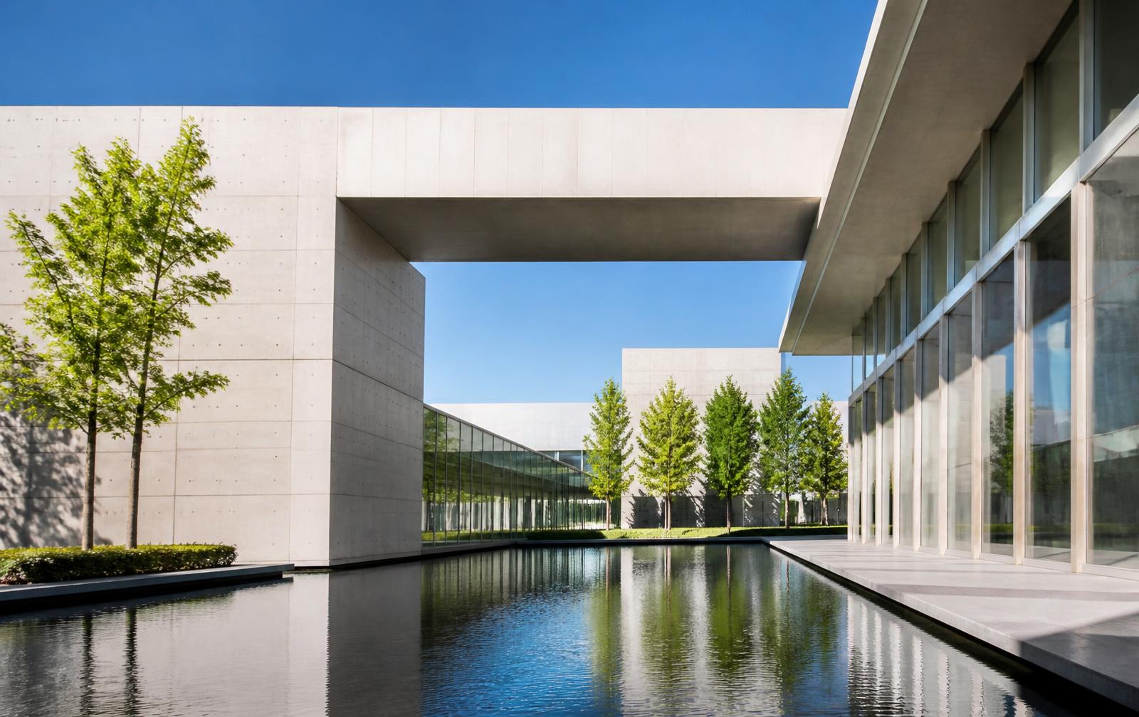 Heller Campusbau aus Sichtbeton und Glas mit Wasserbecken bei Sonnenlicht